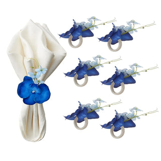 porte serviettes décoratifs orchidées bleues fleurs artificielles tissu texturé élégants serviettes pliées anneaux métalliques