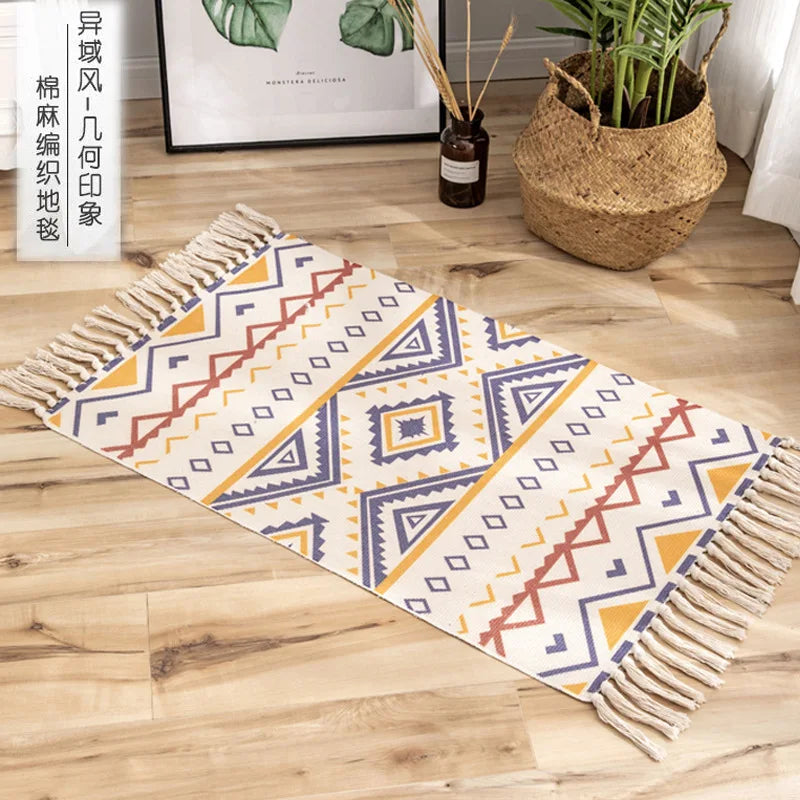 Un tapis de sol décoratif à motifs géométriques colorés dans des tons de jaune, rouge et bleu, posé sur un sol en bois, avec un cadre mural et des plantes en arrière-plan.