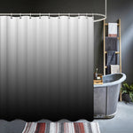 Rideau de douche présentant un dégradé du gris clair au noir, suspendu devant une baignoire de style industriel dans une salle de bain moderne.
