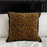Coussin décoratif en tissu velours à motifs floraux dorés sur fond noir, qui apporte une touche d'élégance et de richesse dans un intérieur.