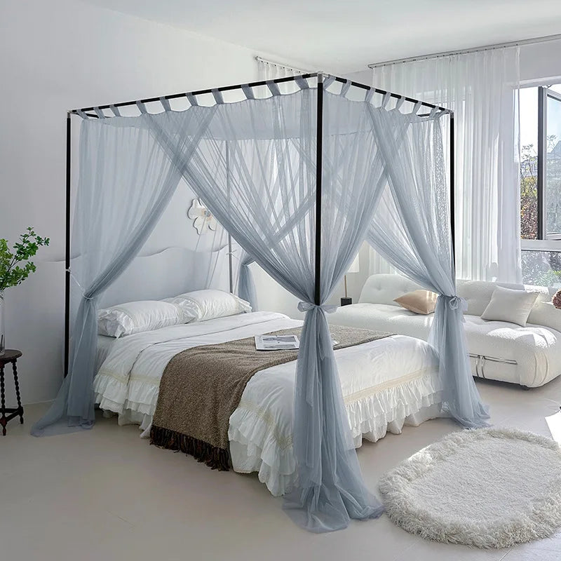 Chambre à coucher élégante et confortable avec un grand lit à baldaquin orné de rideaux gris aériens, créant une atmosphère sereine et relaxante.