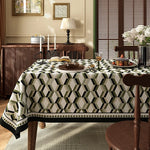 Une salle à manger élégante avec un décor vintage, une table couverte d'un motif géométrique moderne et des accessoires de style rustique.