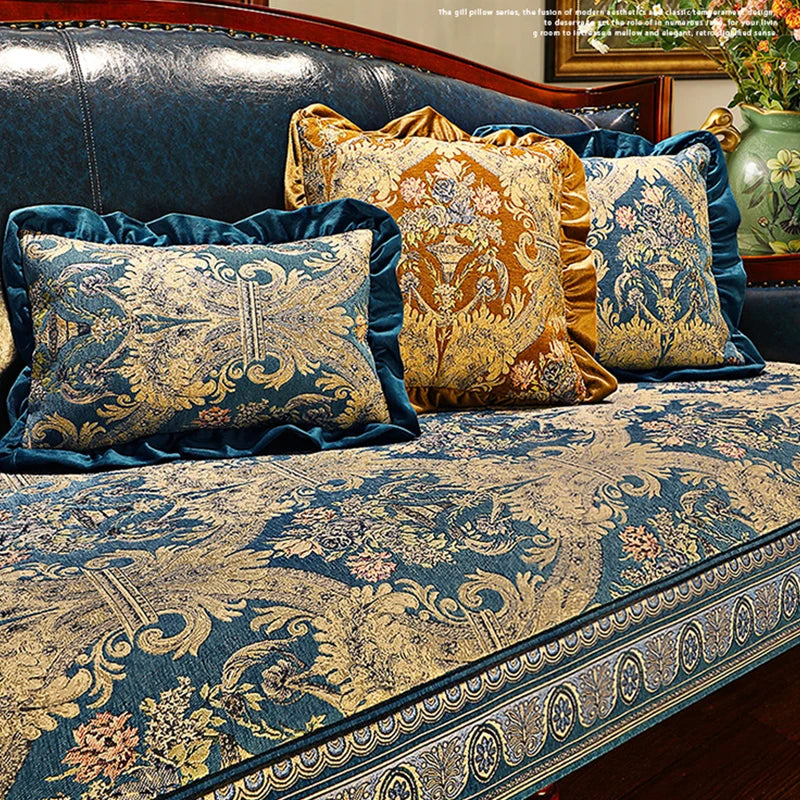 Un canapé confortable avec des coussins décoratifs aux motifs floraux dorés et bleu marine, créant une ambiance élégante et sophistiquée dans la pièce.
