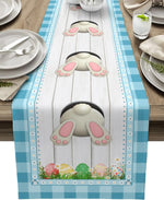 Un chemin de table décoré de motifs colorés de pattes de lapins et d'oeufs de Pâques sur un fond gris clair, créant une ambiance chaleureuse et printanière.
