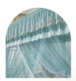 Rideau de lit rond en dentelle et mousseline de couleur bleu-vert, avec de multiples couches de volants et de motifs délicats, créant une ambiance douce et romantique.