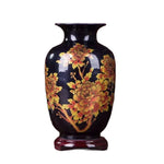 Un vase en céramique noire décoré de fleurs jaunes et orange épanouies.