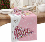 Une table festive avec des assiettes, des verres et une nappe rose décorée de motifs hivernaux et d'un tapis de table en forme de bonhomme de neige.