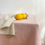 Sur un linge de table texturé de nuances subtiles, deux citrons jaunes brillants offrent une touche de fraîcheur et de vivacité.