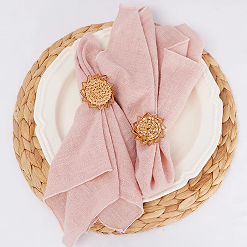 Assiette en osier avec serviette rose pastel et décorations florales dorées.
