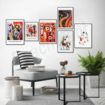 Cette image présente un mur décoré avec des affiches d'art abstrait colorées et dynamiques, créées par l'artiste Alexander Calder. L'espace comprend également un fauteuil gris, une table basse et des accessoires de décoration, créant une ambiance moderne et épurée.