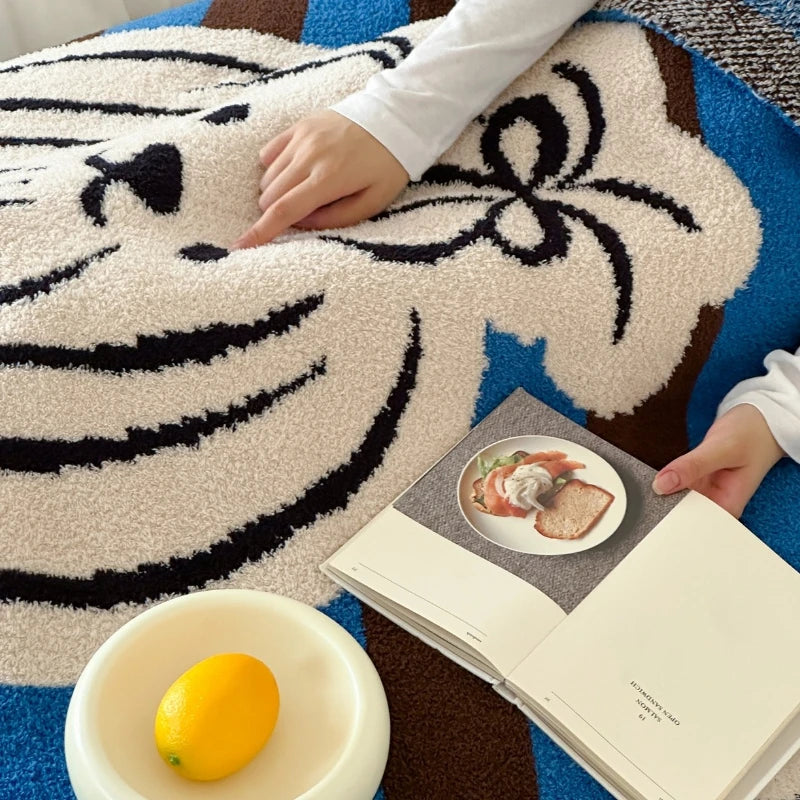 Gros plan sur un tapis de sol orné de motifs noirs et bleus, avec un livre ouvert et un citron sur une assiette à côté.