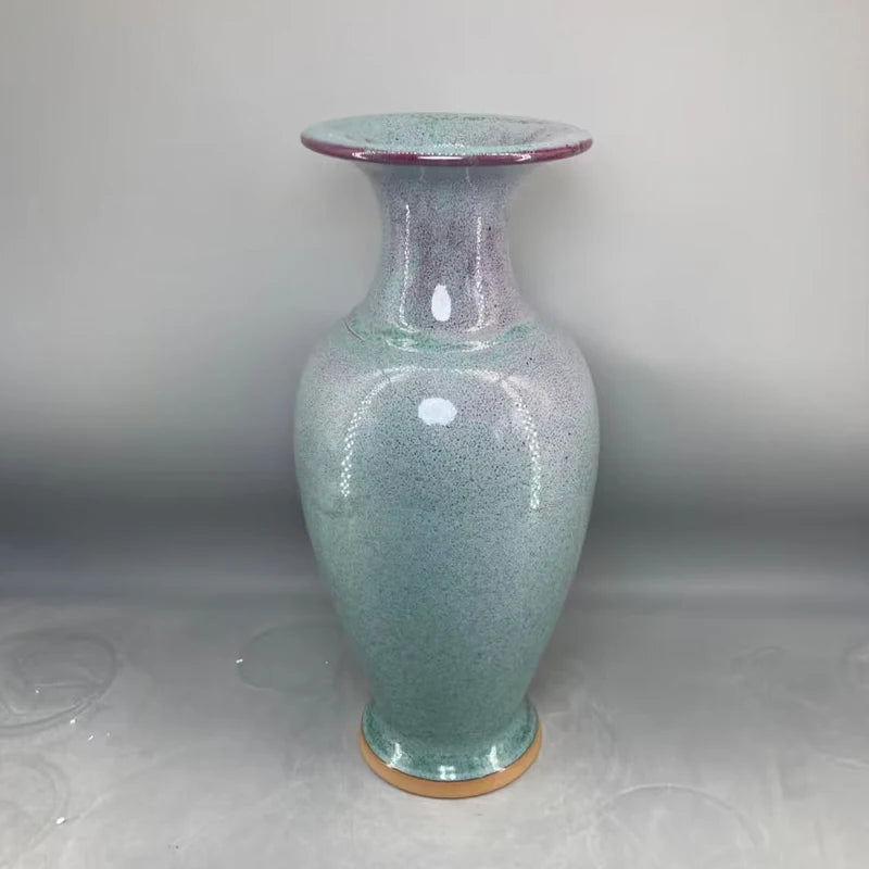 Un vase en verre coloré avec un design texturé et une forme élégante, posé sur une surface brillante.