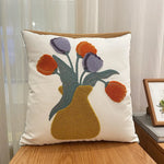 Coussin décoratif avec un bouquet de tulipes colorées dans un vase en forme de poire.