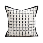 Coussin décoratif blanc et noir avec un motif géométrique répétitif, parfaitement adapté pour une décoration de style contemporain.