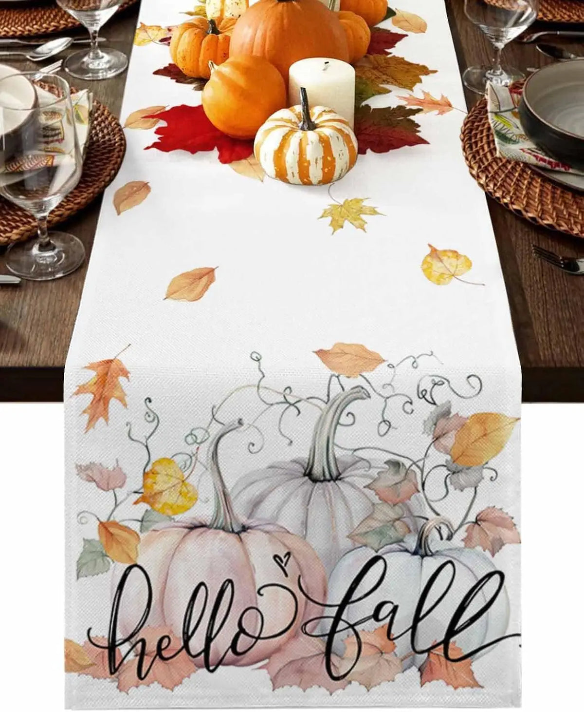 Table de fête d'automne avec des citrouilles, des bougies et des feuilles d'érable tombées, soulignant l'arrivée de la saison automnale.