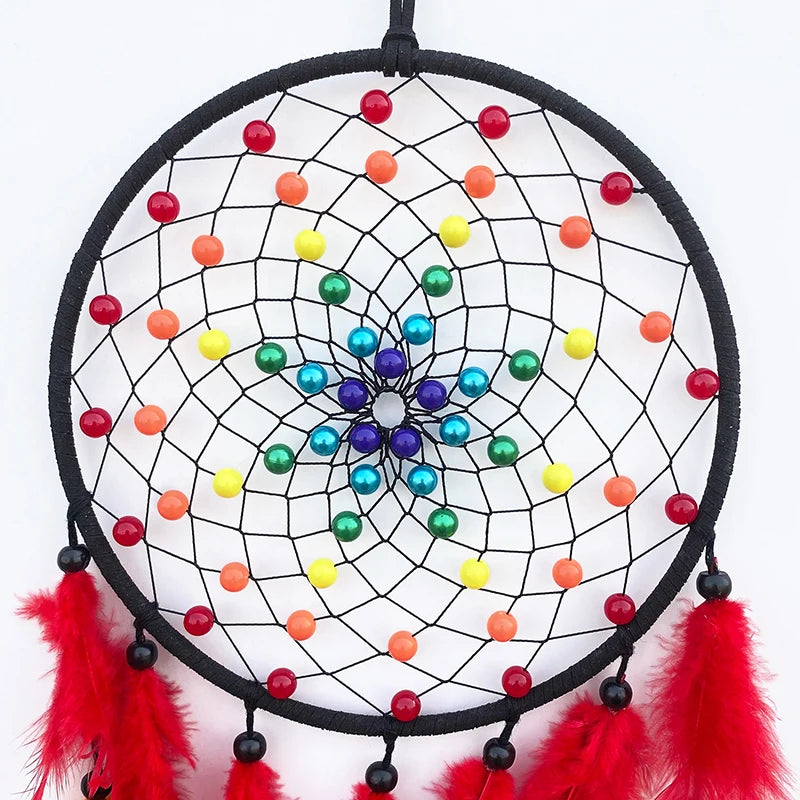 Un capteur de rêves coloré et décoratif suspendu avec des perles multicolores, des plumes rouges et une fleur au centre.