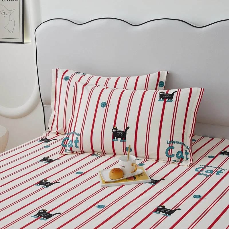 Une chambre douillette avec des coussins et une couverture rayée décorés de motifs de chats mignons, créant une ambiance chaleureuse et ludique.