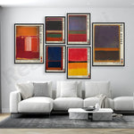 Ensemble de toiles abstraites aux couleurs vives accrochées sur un mur blanc dans un salon moderne avec un canapé blanc et une table basse en marbre.