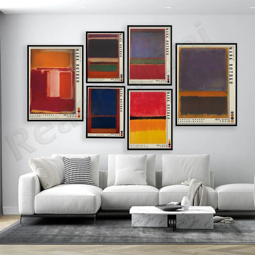 Ensemble de toiles abstraites aux couleurs vives accrochées sur un mur blanc dans un salon moderne avec un canapé blanc et une table basse en marbre.