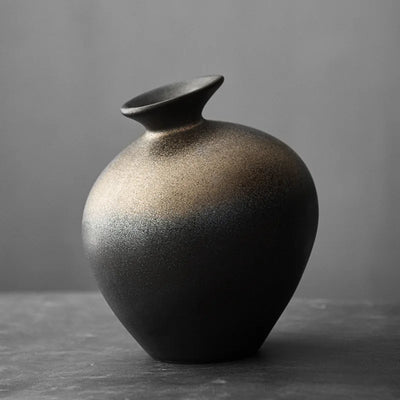 Vase en terre cuite noir imitation pierre sur table en bois