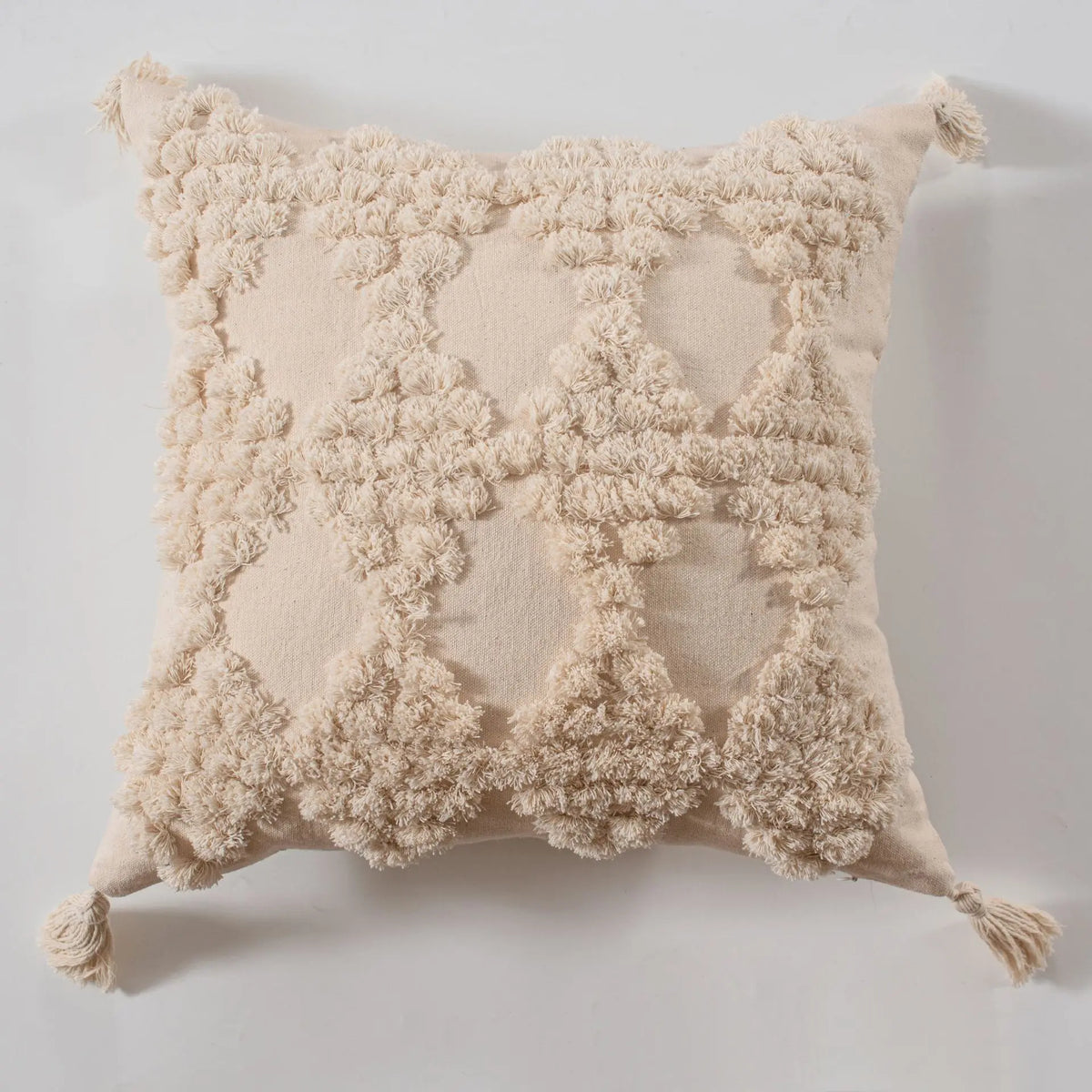 Coussin décoratif beige moelleux avec motif de pompons texturés.