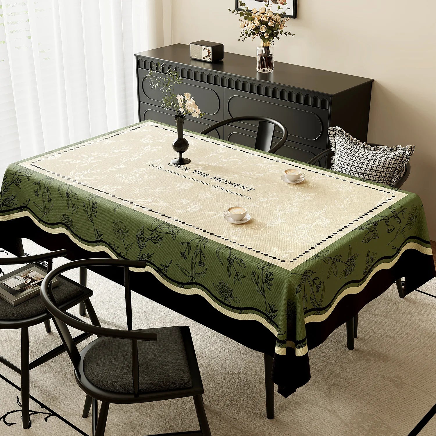 Une table élégante avec un décor floral sur une nappe verte, avec un meuble en bois sombre et un vase de fleurs blanches sur la surface.