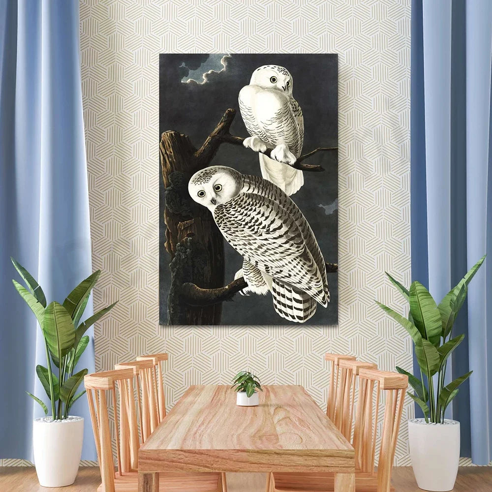 Deux hiboux blancs perchés sur une branche sombre, sous un ciel nuageux, ornement élégant et naturel de cette salle à manger moderne.
