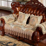 Un canapé en bois sculpté richement orné, avec des coussins en tissu fleuri décoré de dentelle, créant un style élégant et vintage dans cette pièce.