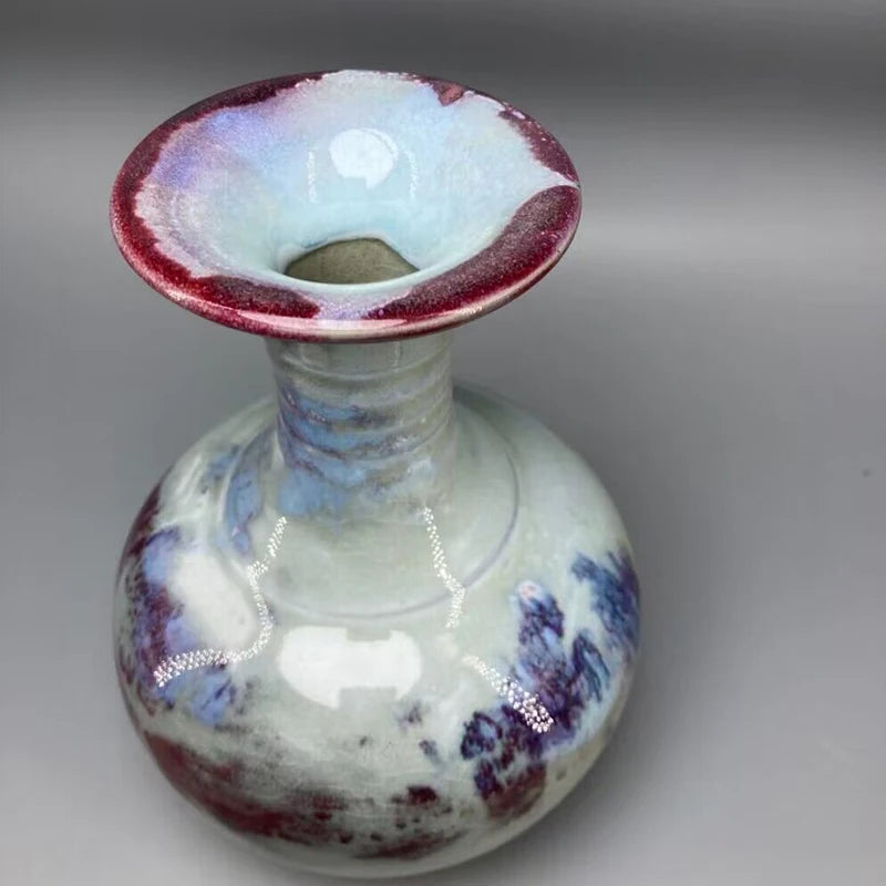 Le vase en verre émaillé aux couleurs violettes et bleutées présente un design artistique et vintage.