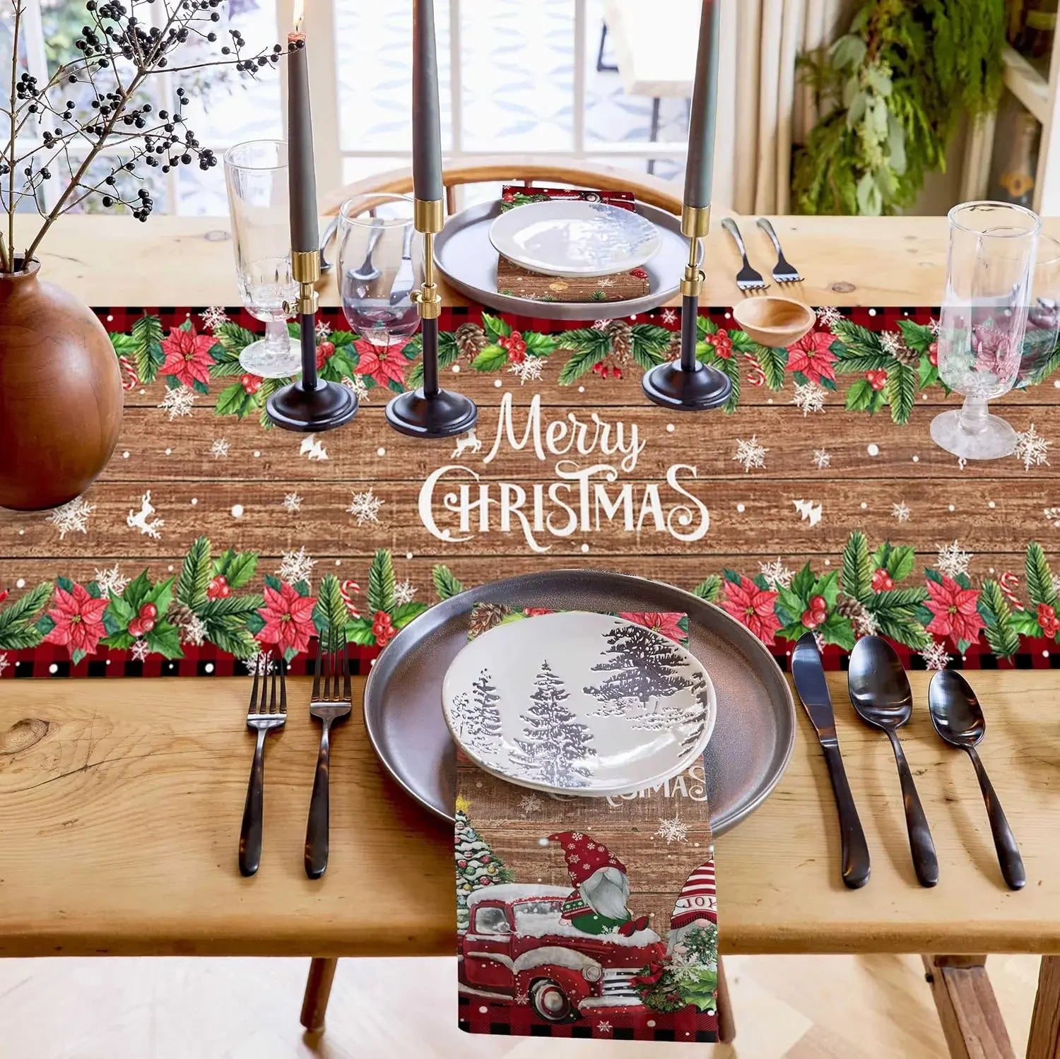 Jolie table de Noël avec des décorations festives, un texte « Joyeux Noël » et des assiettes avec des motifs de sapins et de camions rouges.