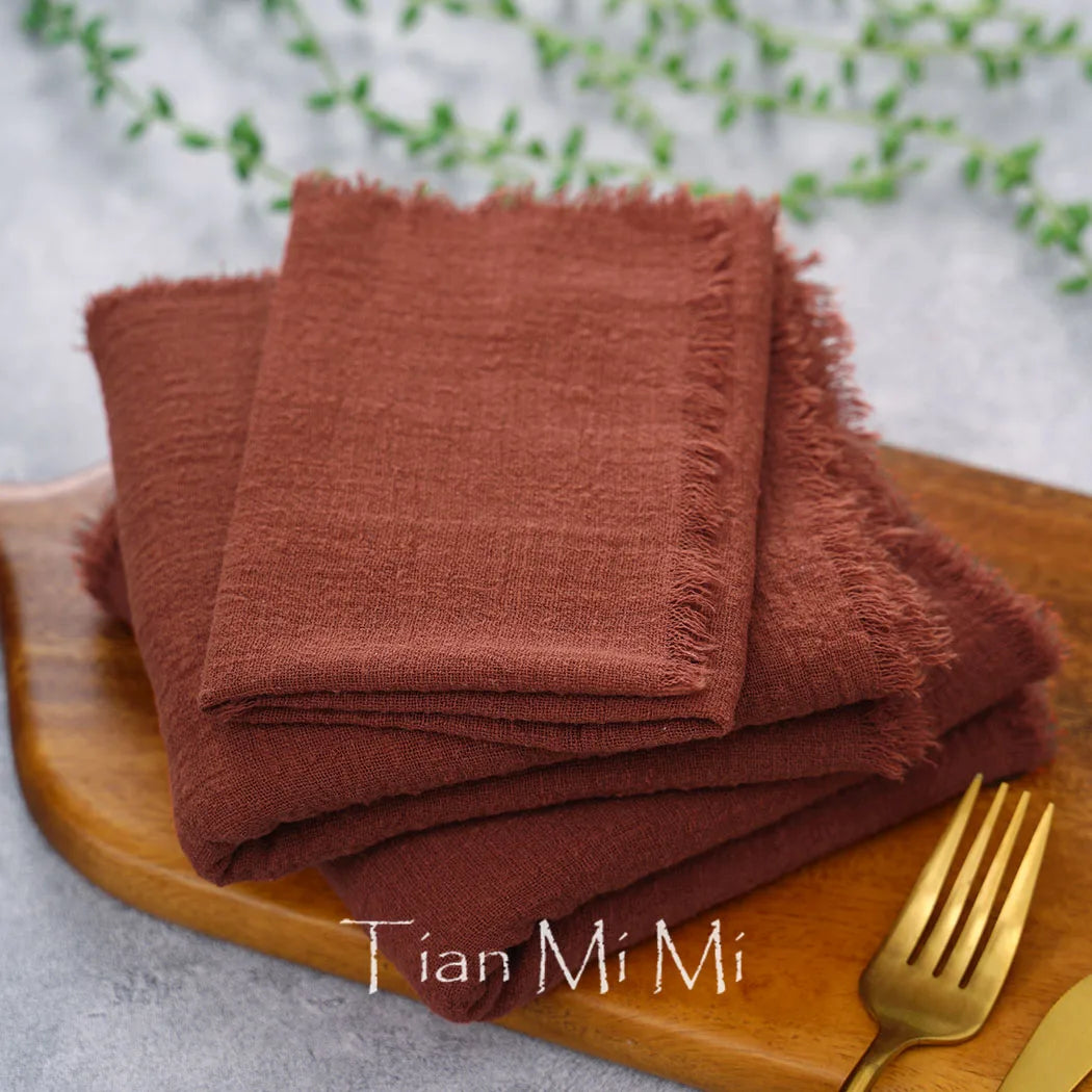 Des serviettes de couleur brune, avec un bord frangé, sont disposées sur un plateau en bois. Le texte "Tian Mi Mi" est visible sur le plateau.