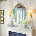 Le miroir vintage décoré de vert pâle et de détails dorés, accroché au-dessus d'un meuble blanc, confère à cette pièce une atmosphère chaleureuse et élégante.
