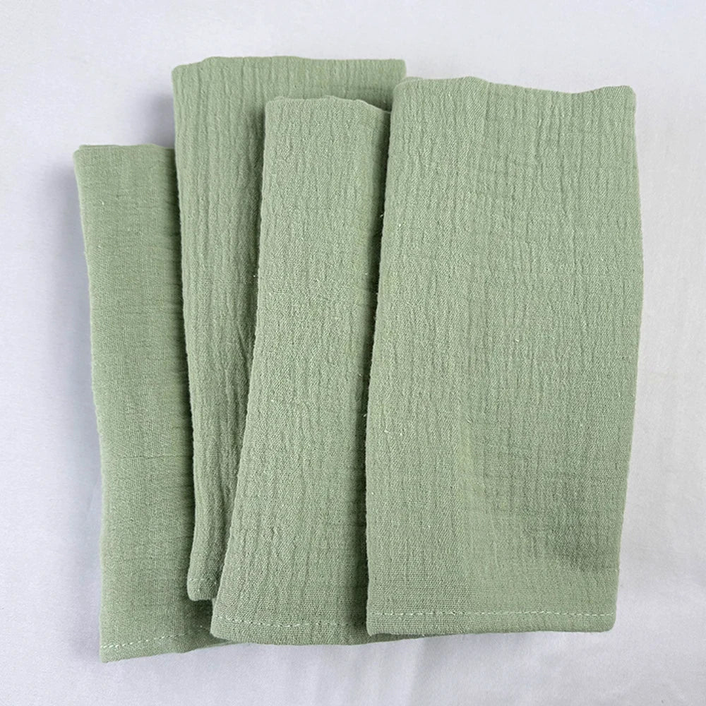 Des piles de serviettes de bain vertes posées sur un fond blanc.