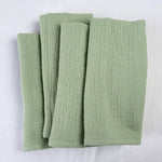 Des piles de serviettes de bain vertes posées sur un fond blanc.