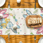 Une table en bois avec un motif coloré de Pâques, décorée de couverts et d'un morceau de pain doré.