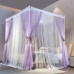 L'image montre un lit à baldaquin en violet et blanc avec des rideaux transparents, créant une atmosphère romantique et élégante dans la chambre.