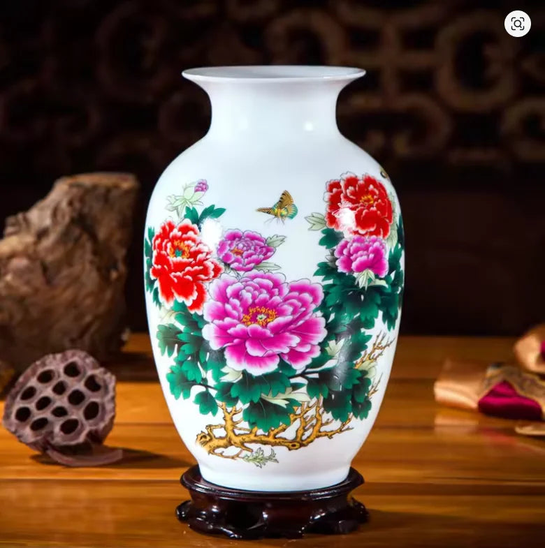Un vase orné de fleurs de pivoines colorées et d'un papillon, posé sur un support en bois sombre.
