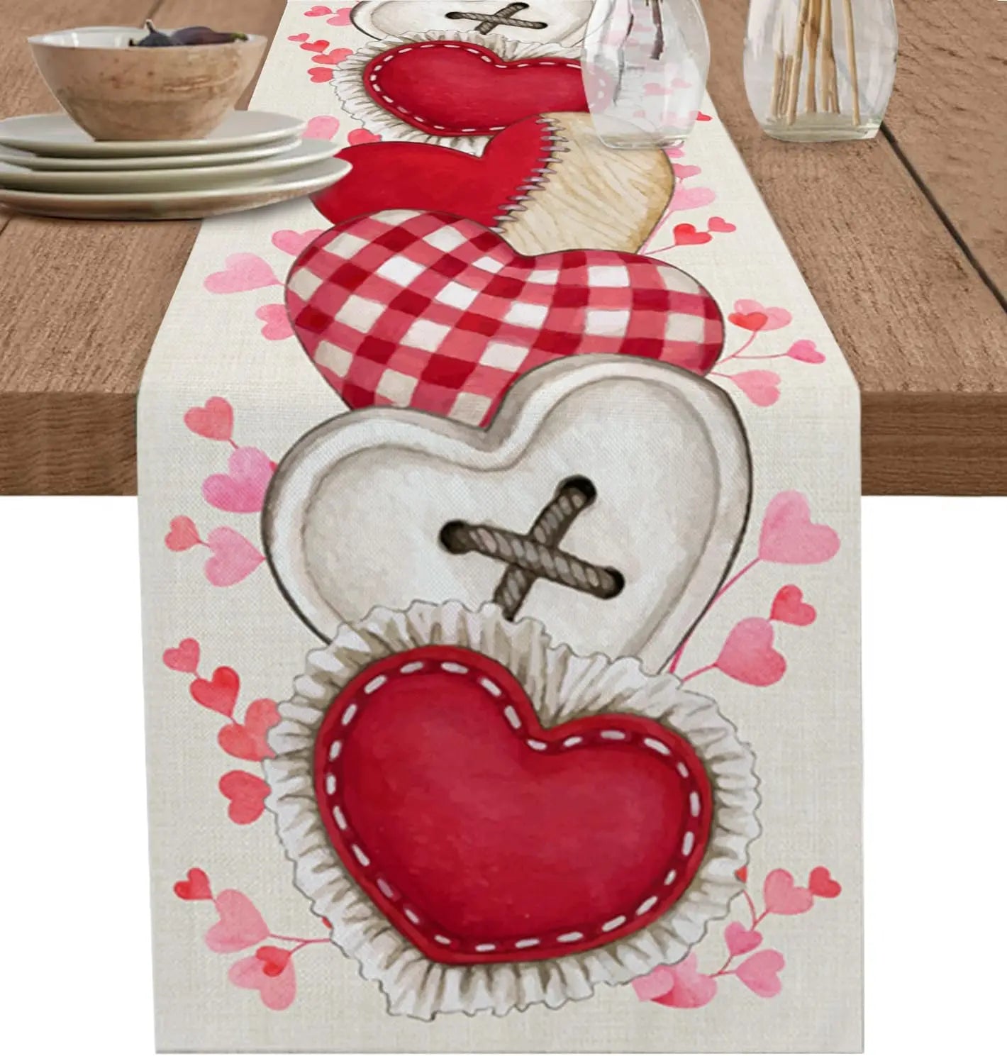 Cette image met en scène un chemin de table orné de motifs de coeurs rouges et roses, avec des coeurs brodés et des motifs géométriques sur un fond blanc, créant une ambiance romantique et festive.