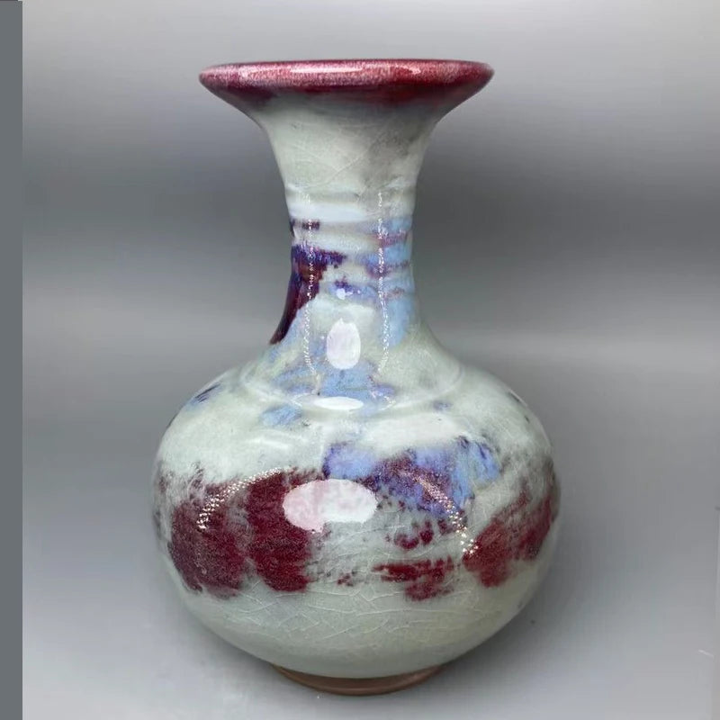 Vase artisanal de style rétro avec des motifs floraux abstraits et des couleurs contrastées de rouge, de violet et de bleu, créant une texture et un effet visuel uniques.