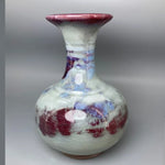 Vase artisanal de style rétro avec des motifs floraux abstraits et des couleurs contrastées de rouge, de violet et de bleu, créant une texture et un effet visuel uniques.