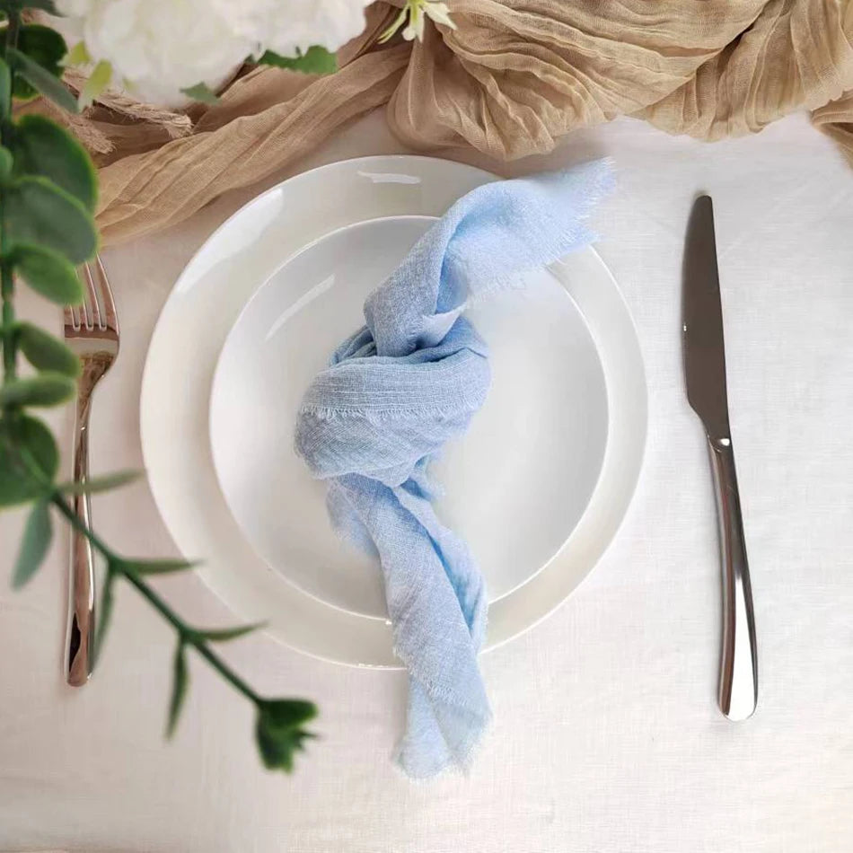 Une élégante table dressée avec une serviette bleu pastel, des couverts et une décoration florale naturelle.
