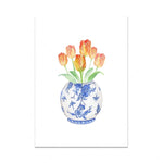 Un bouquet de tulipes orange et jaunes dans un vase en porcelaine bleue et blanche aux motifs floraux.