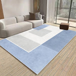 Un tapis géométrique bleu et blanc au style épuré, agrémentant un intérieur moderne et lumineux avec un canapé gris.