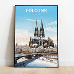 L'image montre une affiche touristique représentant la majestueuse cathédrale de Cologne en Allemagne, avec son architecture gothique imposante et ses deux tours jumelles, entourée de bâtiments et d'un pont qui se reflète dans l'eau.