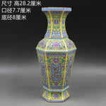 Vase en porcelaine décoré de motifs floraux colorés sur un fond jaune éclatant.