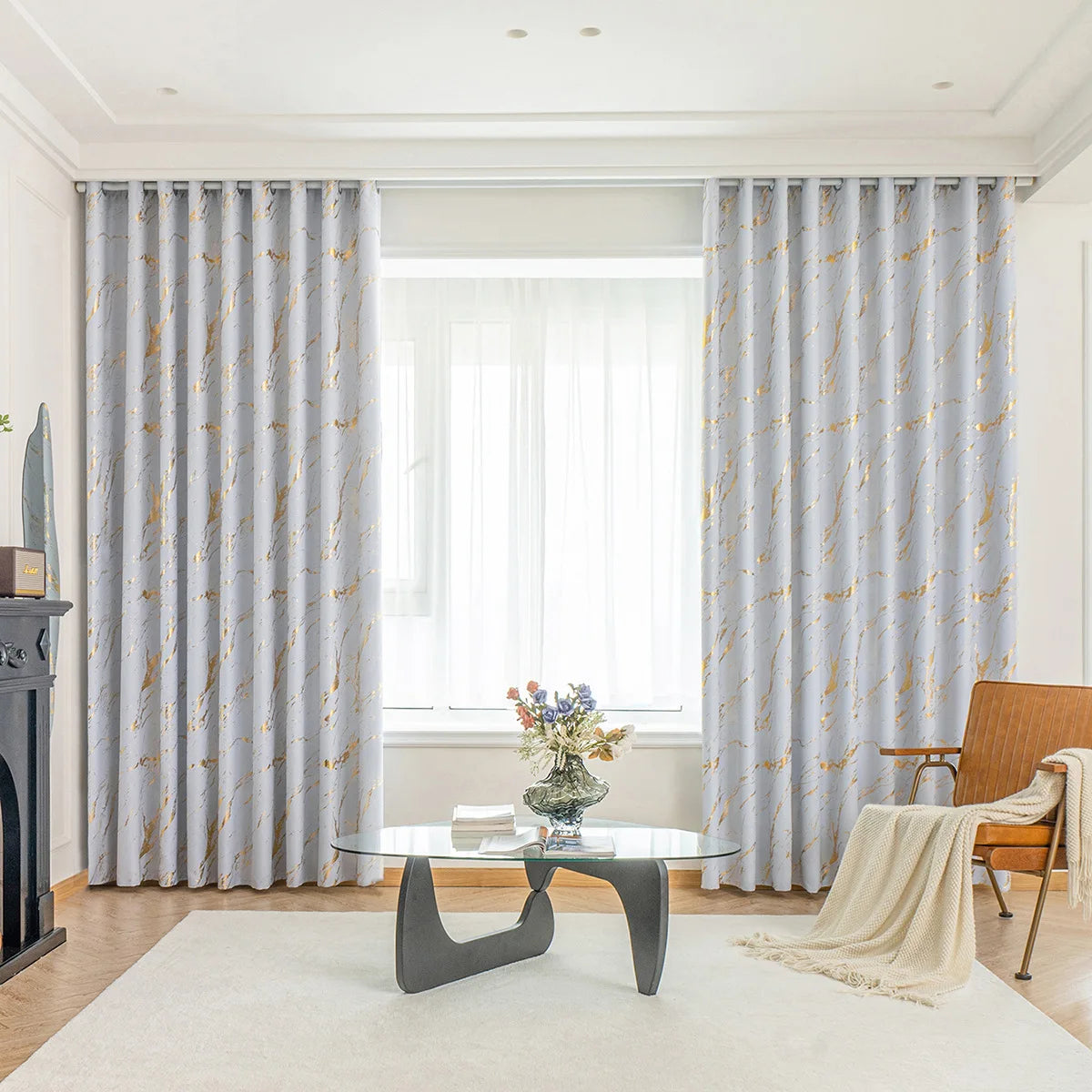 Image représentant une décoration d'intérieur élaborée avec des rideaux luxueux en tissu de couleur crème, drapés avec style dans un salon spacieux. Les rideaux servent de traitement de fenêtre, ajoutant une intimité et une élégance sophistiquée à l'espace. Le design est accentué par un papier peint à motifs subtils sur les murs et un daybed confortable situé près de la fenêtre. Cette image illustre l'importance des couvertures de fenêtre dans le design d'intérieur.
