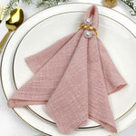 Une élégante serviette de table rose pâle ornée de perles dorées, reflétant un style raffiné pour une table dressée avec goût.