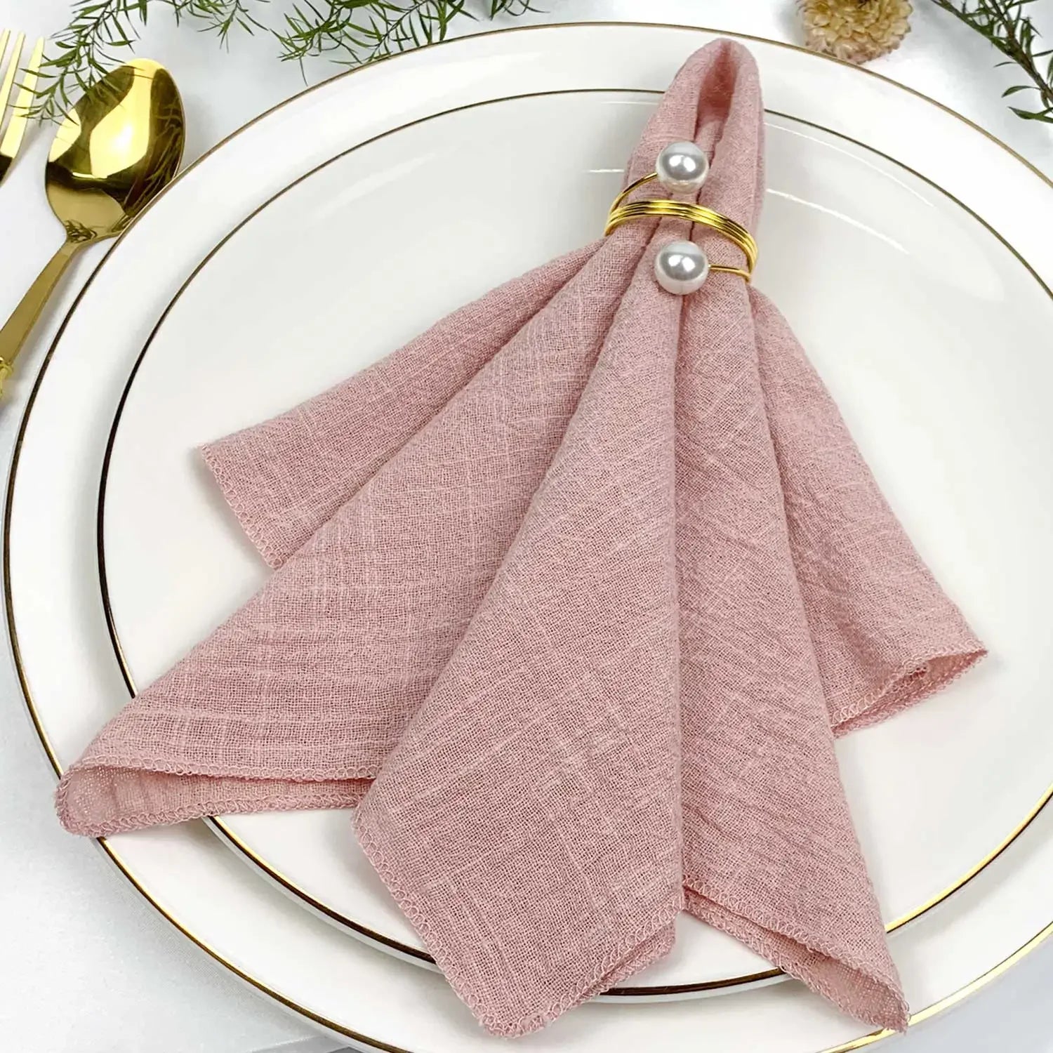 Une élégante serviette de table rose pâle ornée de perles dorées, reflétant un style raffiné pour une table dressée avec goût.