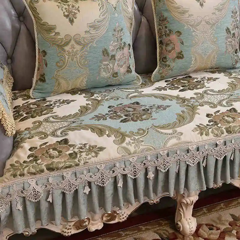 Riche tapisserie de satin bleu-vert et beige ornée de motifs floraux et de dentelle délicate, donnant une atmosphère élégante et chaleureuse à cette pièce d'ameublement.