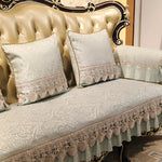 Cette image montre un canapé de style baroque avec des coussins ornés de motifs floraux et de finitions de franges, offrant un aspect luxueux et élégant.